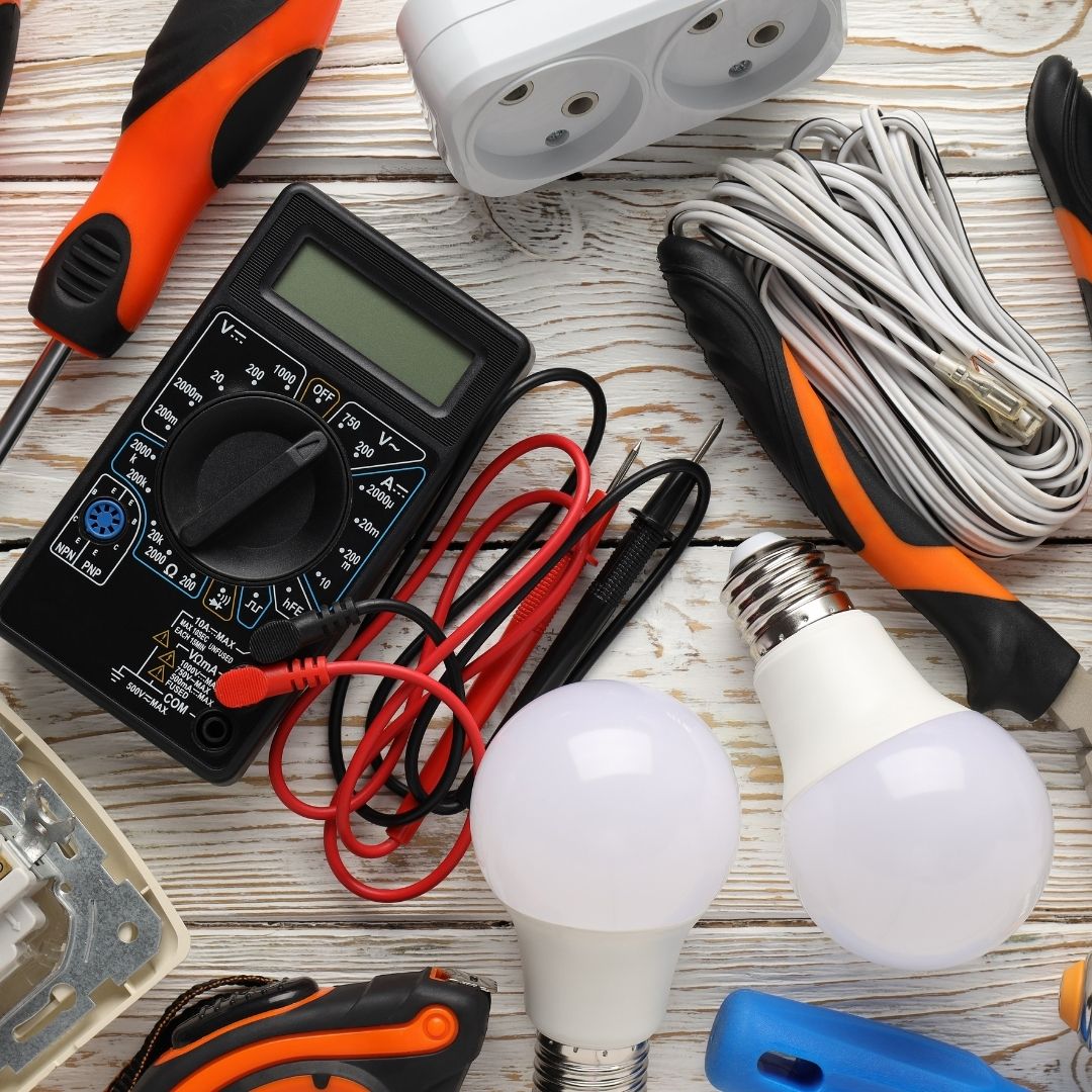 A collection of essential tools used by an Electrician Woolloomooloo, including a multimeter, screwdrivers, wiring, LED bulbs, and other electrical equipment for installations and repairs.