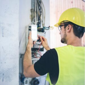 A professional Electrician in Darlinghurst wearing safety gear, testing an electrical panel with a multimeter to ensure proper voltage and wiring safety.