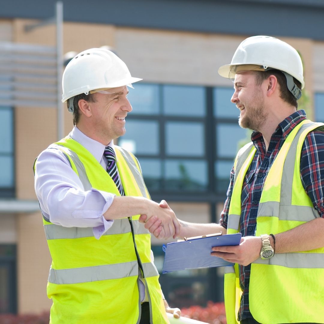 Two electrical contractors in Sydney shaking hands at a construction site, ensuring a successful electrical project with professional expertise and teamwork.