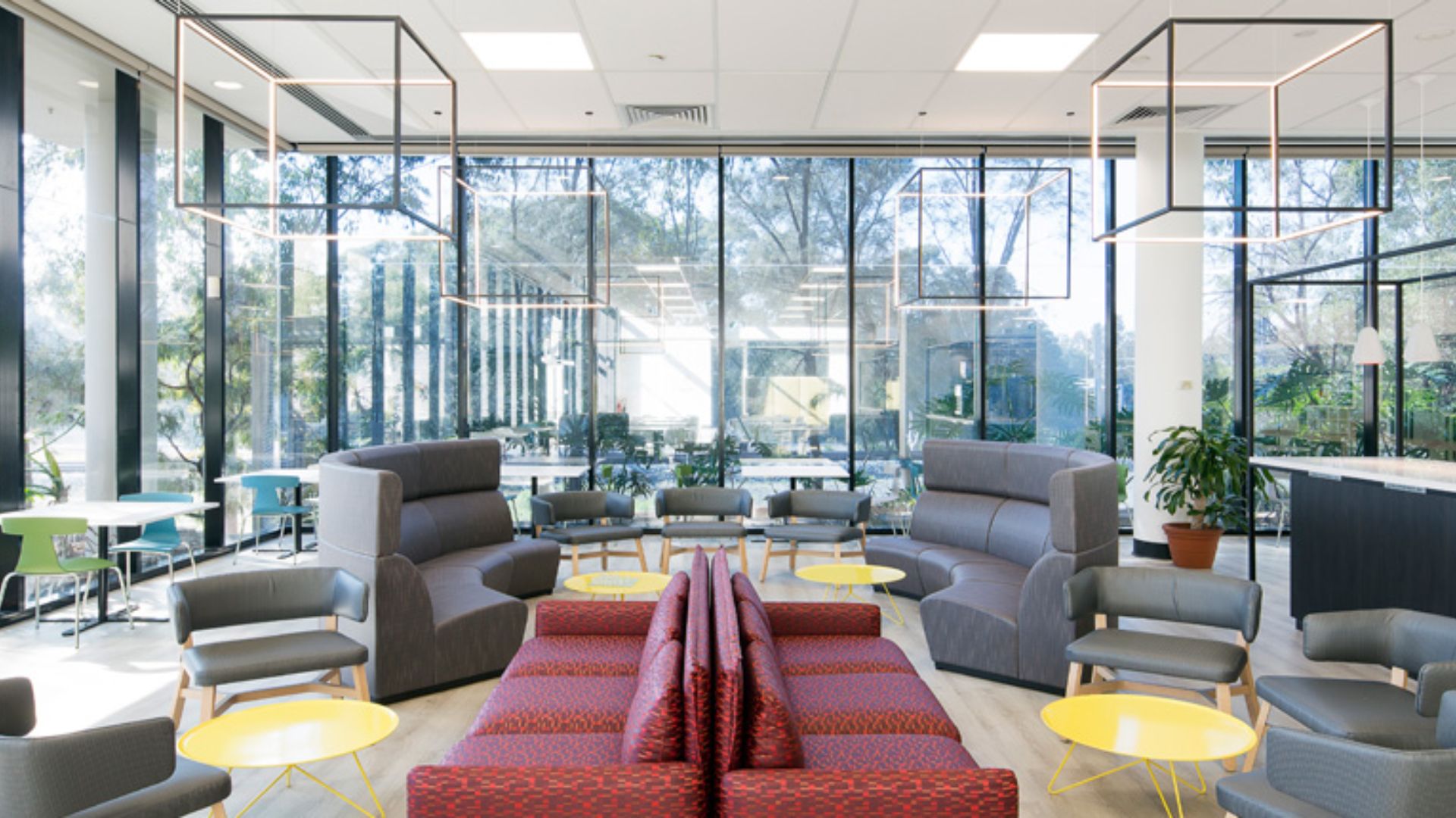 Modern office fitouts in Sydney featuring open lounge seating, glass walls, and stylish lighting design for collaborative spaces.
