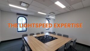 A professional data cabling technician, clearly identified by a high-visibility work vest, focused on installing or maintaining a wall-mounted patch panel. The technician is working on the intricate termination of numerous cables, showcasing the precise, hands-on work required for a compliant and reliable data cabling system in a Sydney office or commercial property.