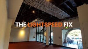 A large commercial space featuring high ceilings and exposed industrial infrastructure (ducts, electrical trays), along with complex modern lighting fixtures and a feature staircase. Servicing these high-access systems presents unique electrical problems. This image emphasizes the need for a specialist commercial electrician equipped to handle the scale and complexity of large commercial structures.