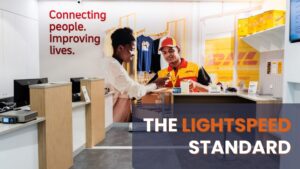 Lightspeed, Your Best Commercial Electrician. An image showing customer service being performed at a clean, professional commercial counter. This area requires faultless power for computers, scales, and POS systems. The text overlay, "THE LIGHTSPEED STANDARD", promotes the company's commitment to fast and quality work, a critical attribute for customers seeking the best commercial electrician who minimizes business downtime.