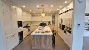 A brightly lit modern kitchen showroom with gold-accented cabinetry and a designer wicker pendant light installed by a Sydney office fit-out electrician.