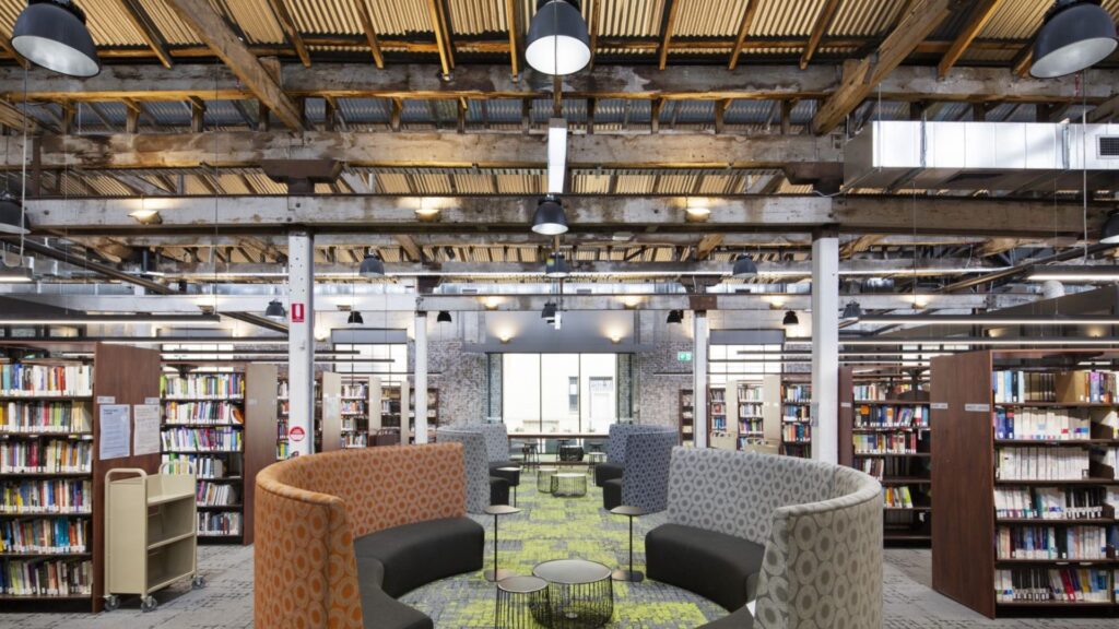 Large-scale industrial library interior featuring exposed timber beams, high-bay pendant lighting, and professional electrical compliance Sydney.