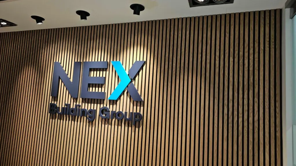 Nex Building Group illuminated office signage on timber slat wall.