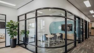 A wide view of a modern corporate office fitout featuring open-plan workstations, custom overhead linear LED lighting strips, and private glass meeting rooms.