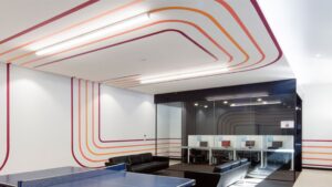 Modern commercial office interior featuring custom overhead LED strip lighting and glass partition office spaces, demonstrating work by a commercial vs residential electrician, by Lightspeed Electrical.